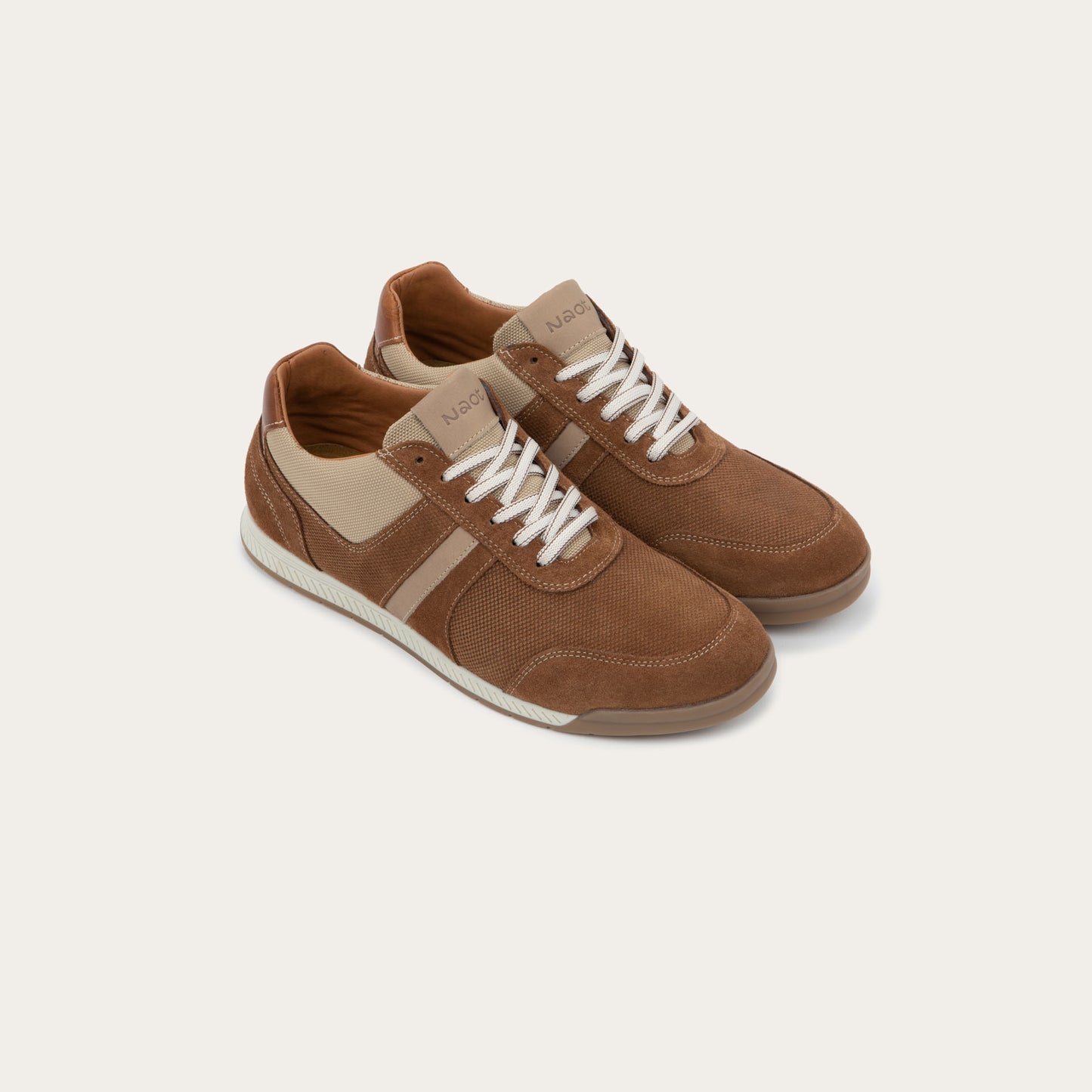 Pair of  brown and beige sneakers on a brown sole.