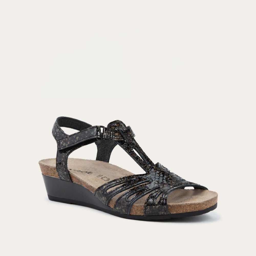 Angled profile view of a  reptile printed wedge sandal with strappy design, open toe, and adjustable ankle strap on a cork footbed.