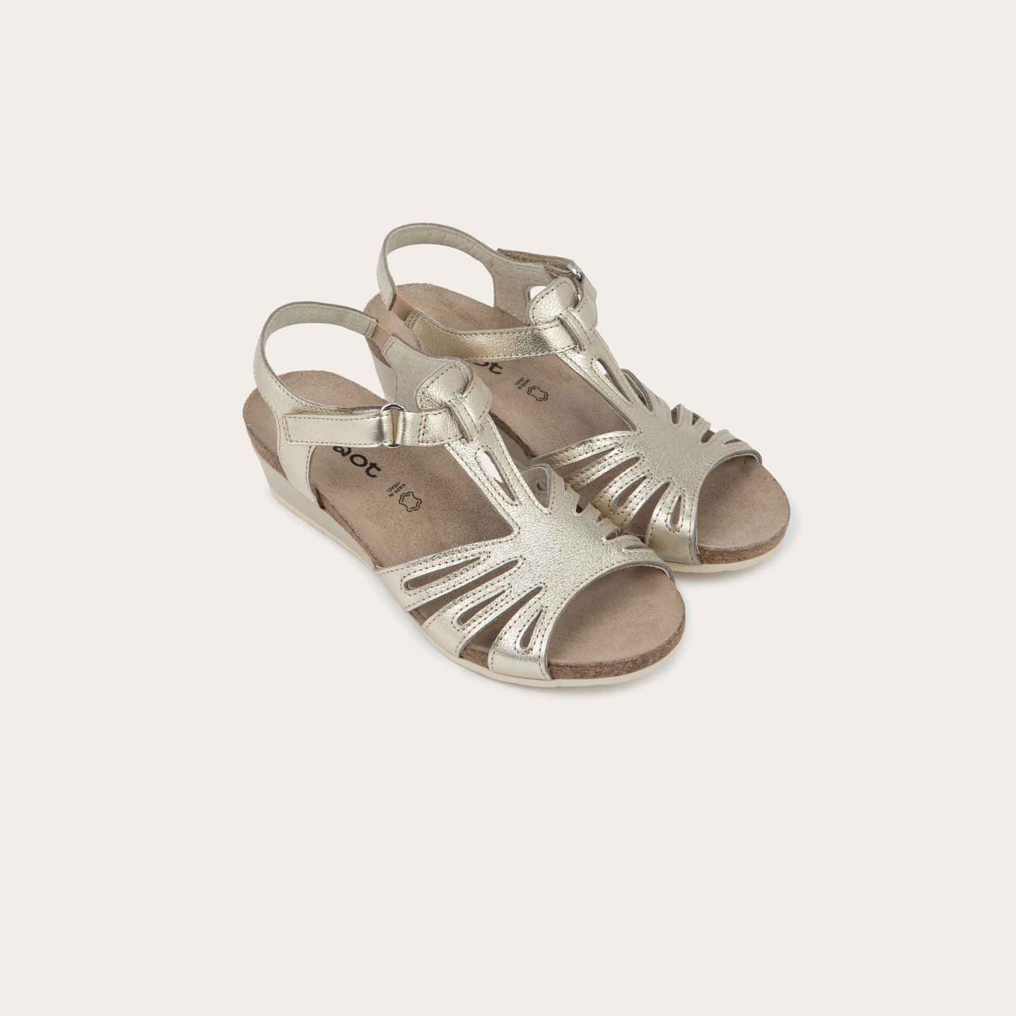 A pair of gold wedge sandals with strappy design, open toe, and adjustable ankle strap on a cork footbed.