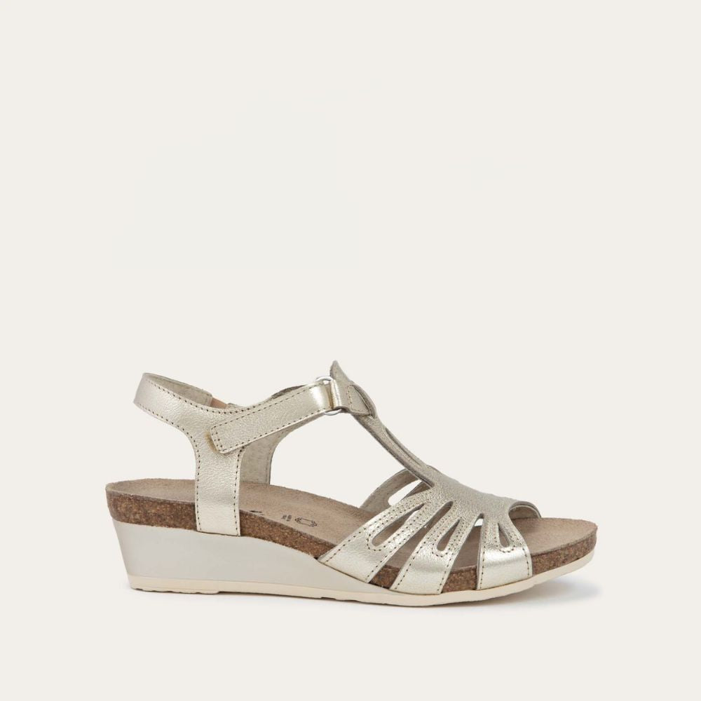 Angled profile view of a gold wedge sandal with strappy design, open toe, and adjustable ankle strap on a cork footbed.