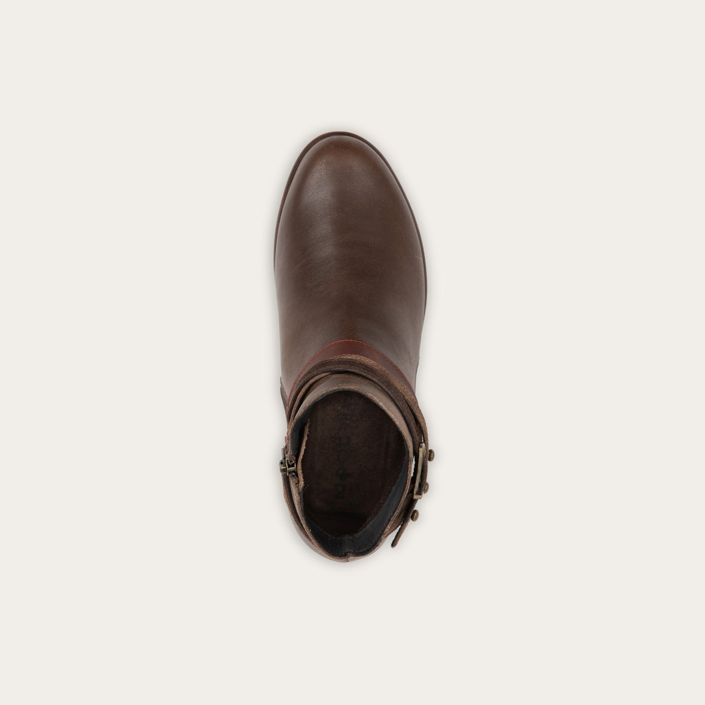 Top view of a brown leather ankle boot with two decorative straps and brass buckles. The boot has a low heel and a smooth, polished finish, conveying a stylish look.