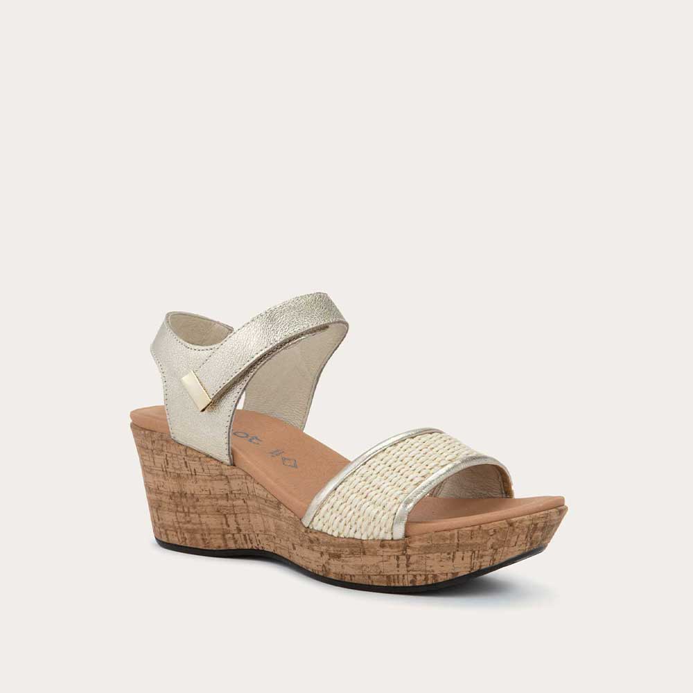 Angled profile view of a wedge heeled sandal with a gold leather ankle strap, and woven beige front strap