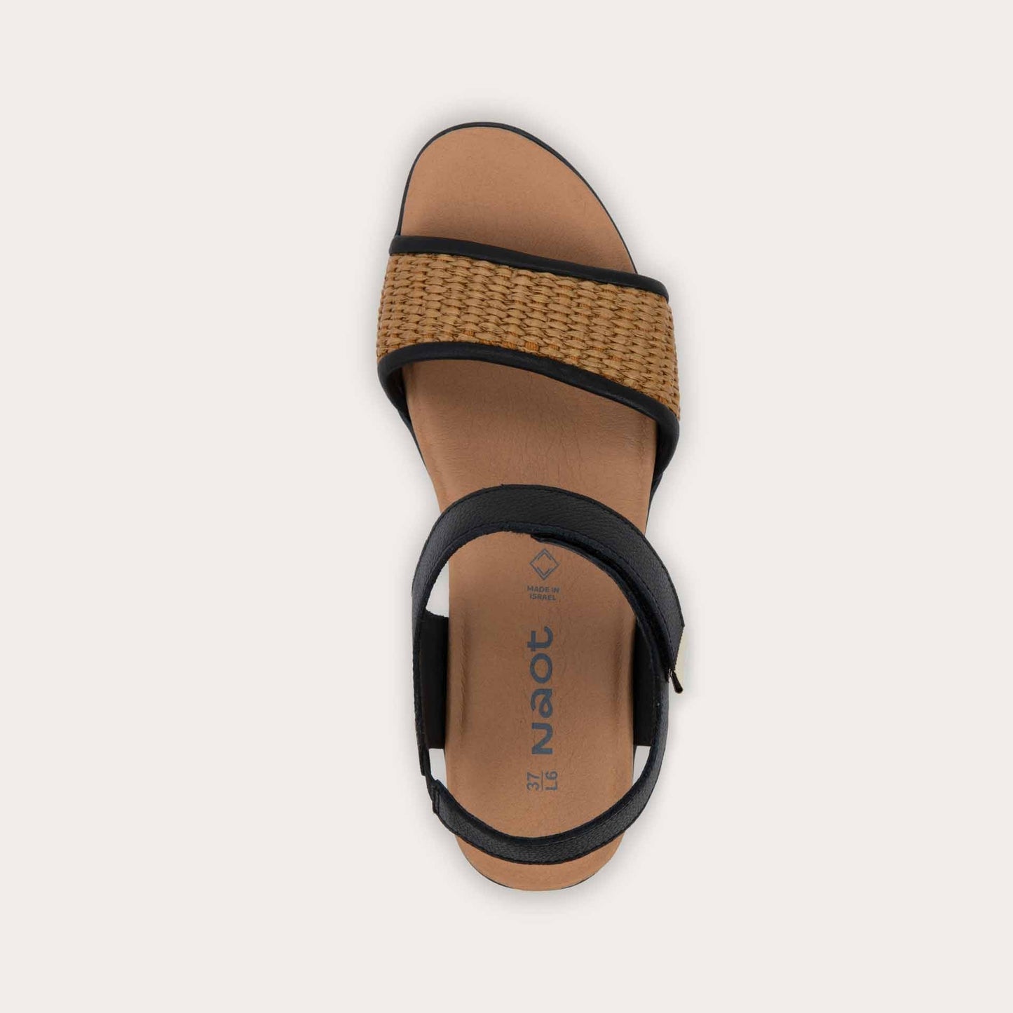 Top view of a view of a wedge heeled sandal with a black leather ankle strap, and woven tan front strap.