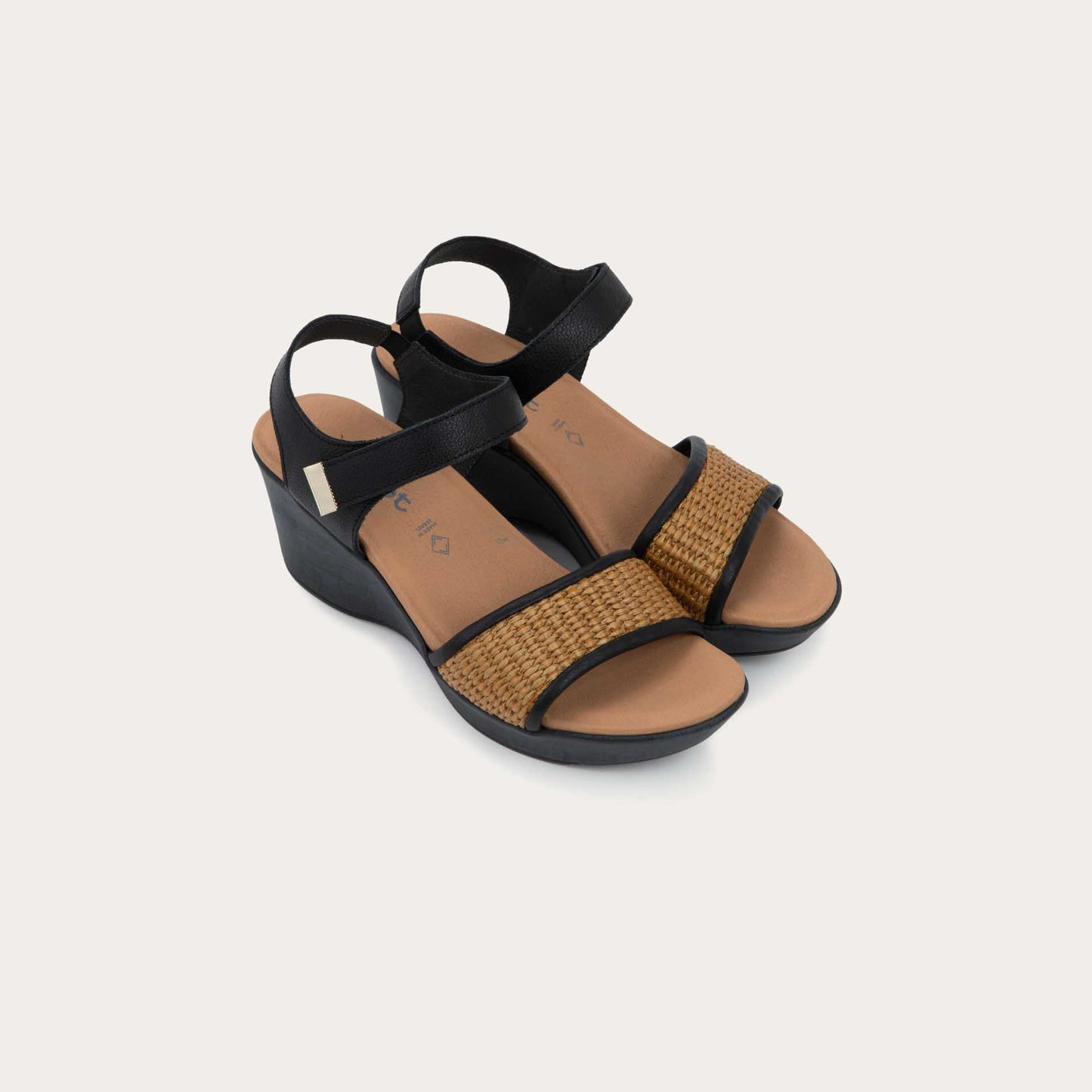 Pair of wedge heeled sandals with a black leather ankle strap, and woven tan front strap