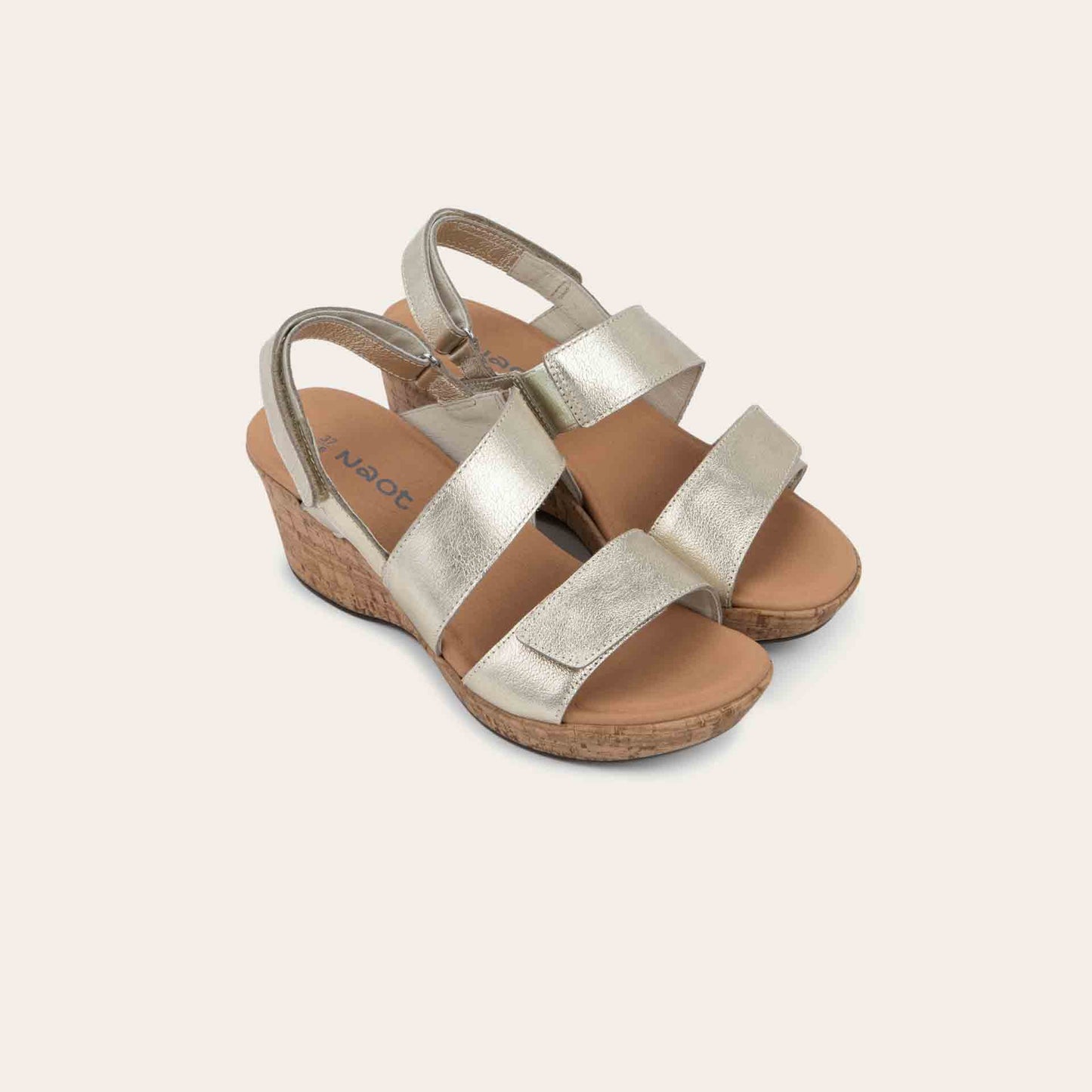 Pair gold sandals with metallic straps on a cork wedge sole. Features an open toe and wedge heel.