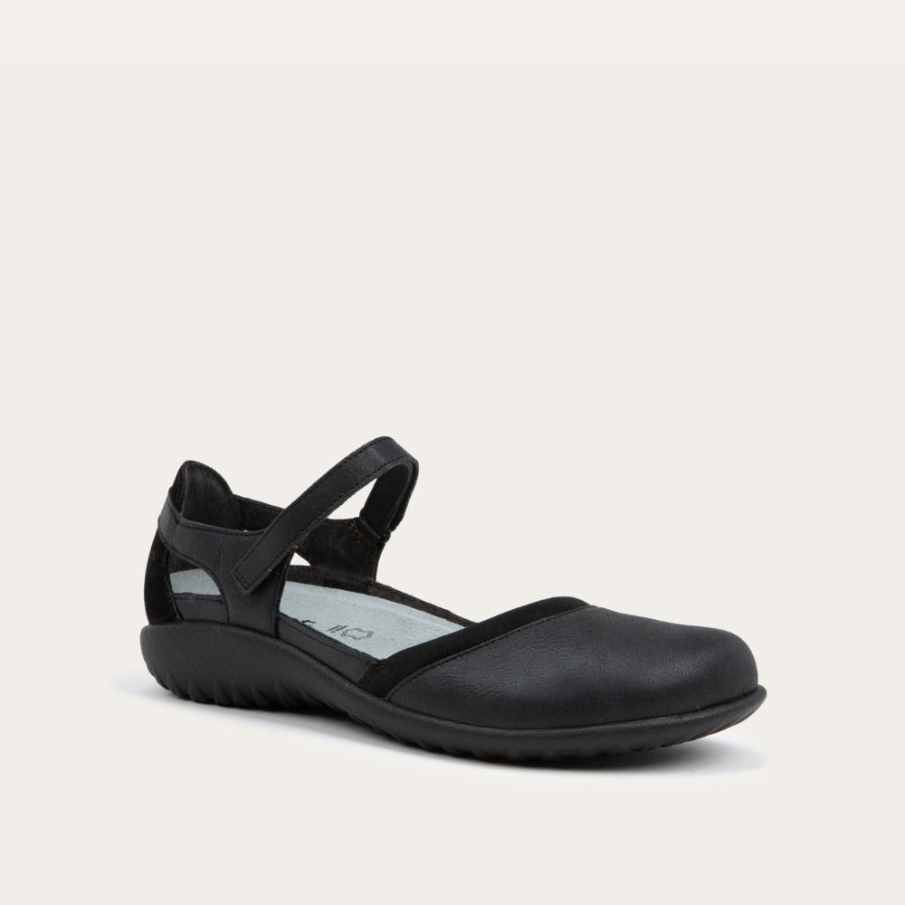 Angled profile view of a black Mary Jane featuring contrasting materials and cutouts by the heel on a dark sole.