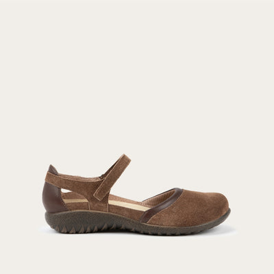 Profile view of a brown Mary Jane featuring contrasting materials and cutouts by the heel on a dark sole.