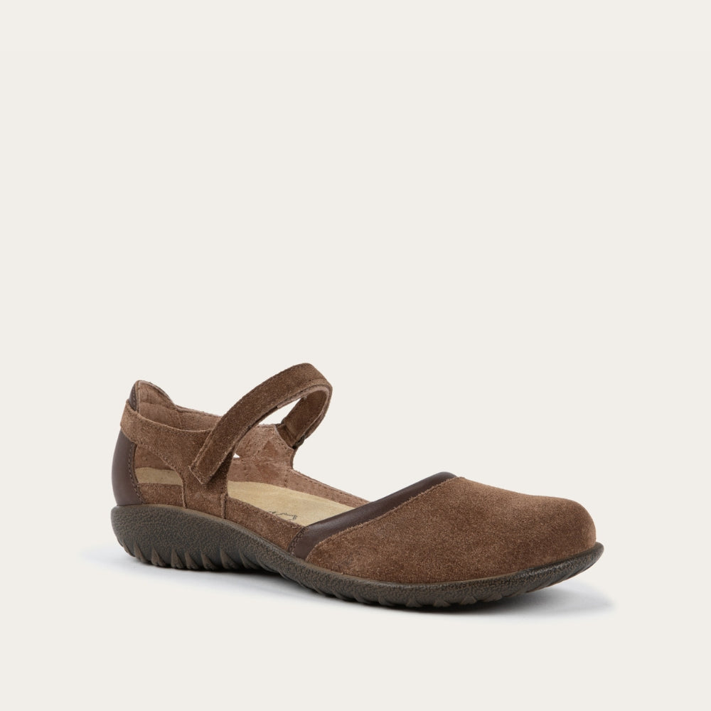 Angled profile view of a brown Mary Jane featuring contrasting materials and cutouts by the heel on a dark sole.