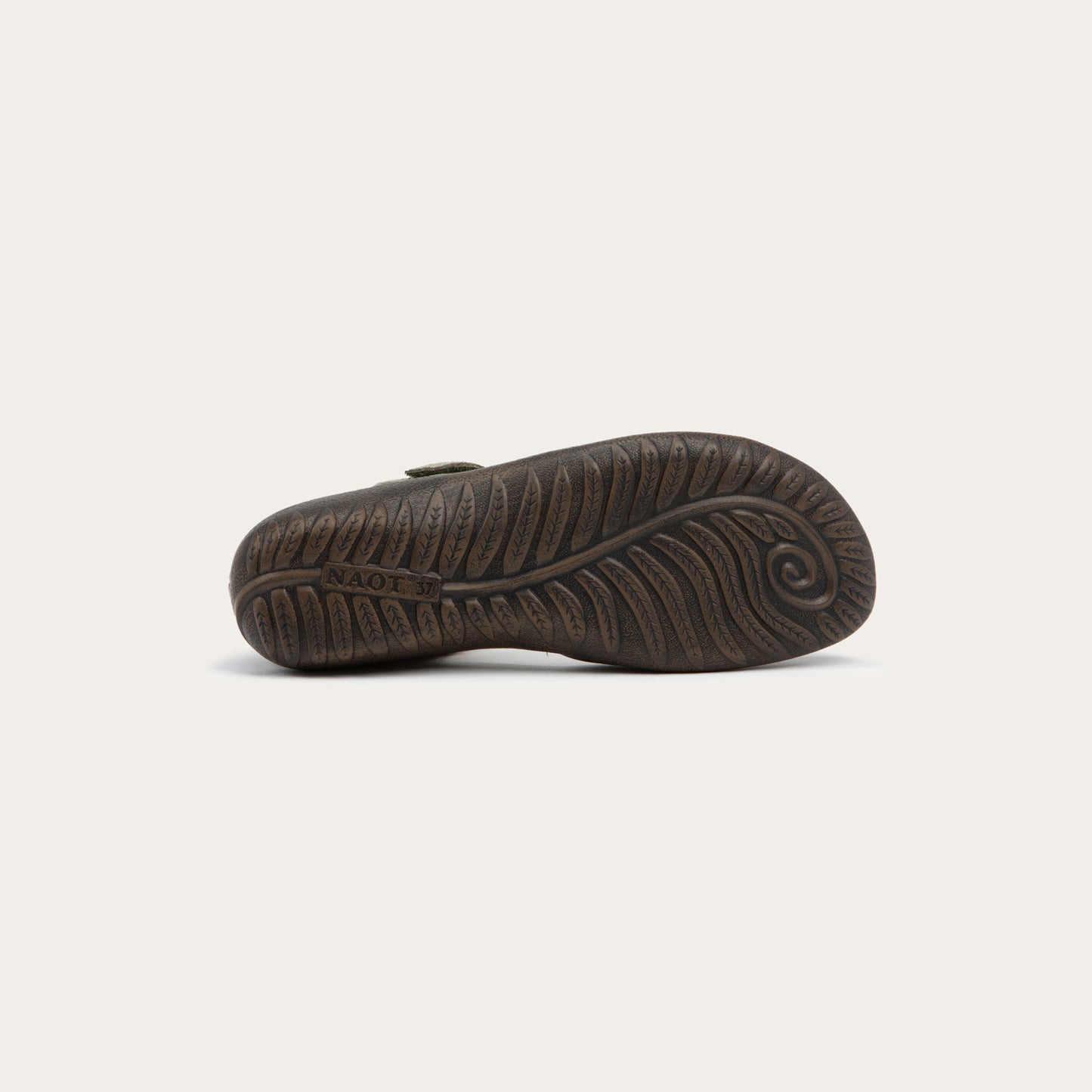 Bottom view of a green Mary Jane featuring contrasting materials and cutouts by the heel on a dark sole.