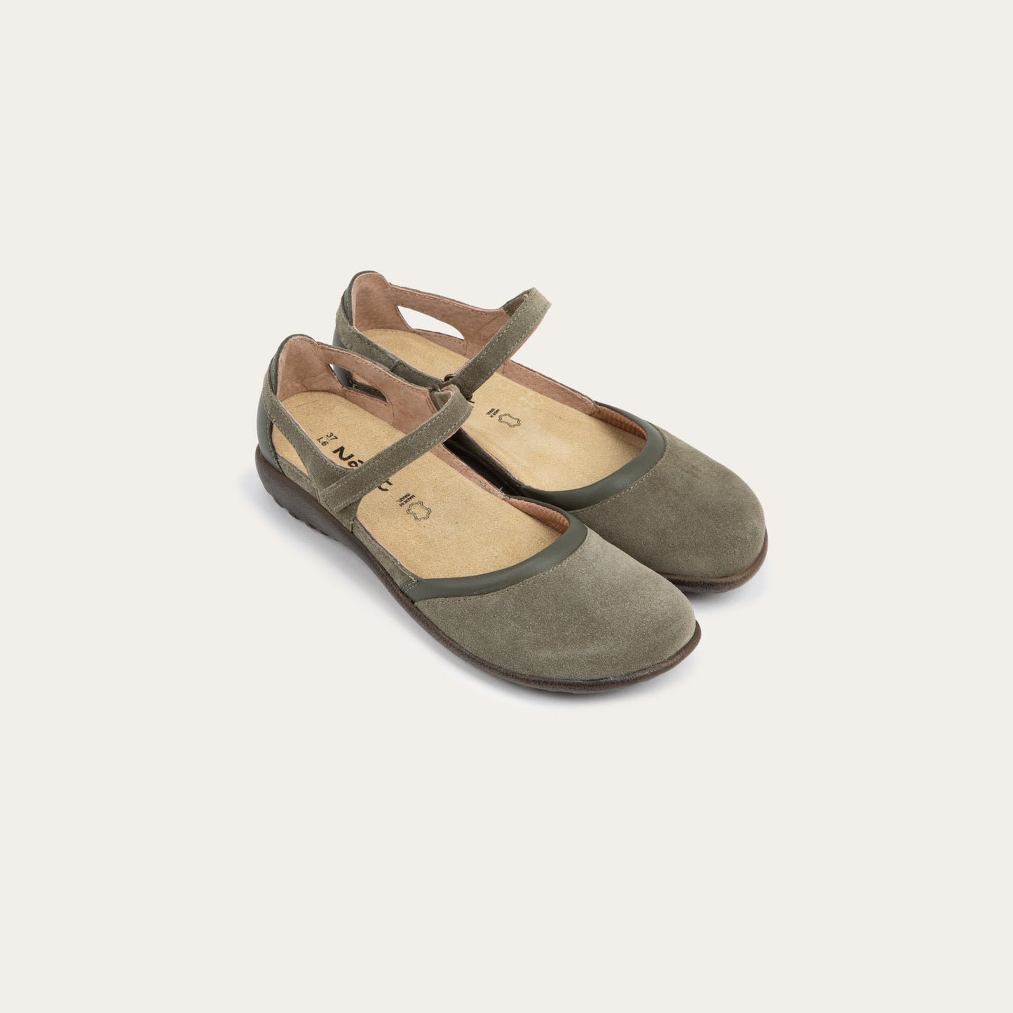 Pair of  green Mary Janes featuring contrasting materials and cutouts by the heel on a dark sole.
