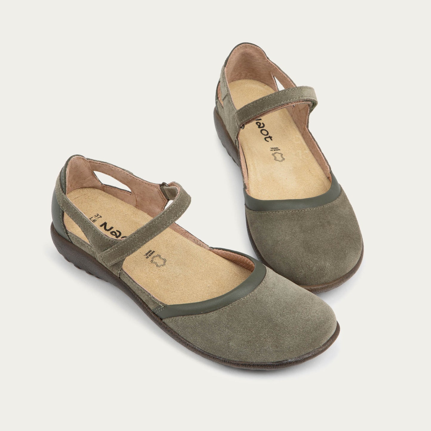 Pair of  green Mary Janes featuring contrasting materials and cutouts by the heel on a dark sole.