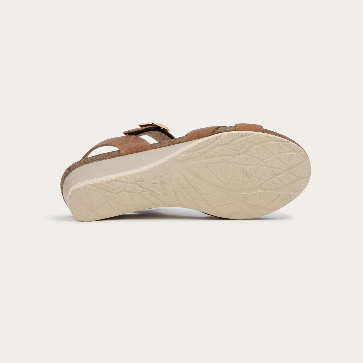 Bottom view of a cork footbed,  brown wedge sandal with cross straps and a gold buckle on the ankle strap. 