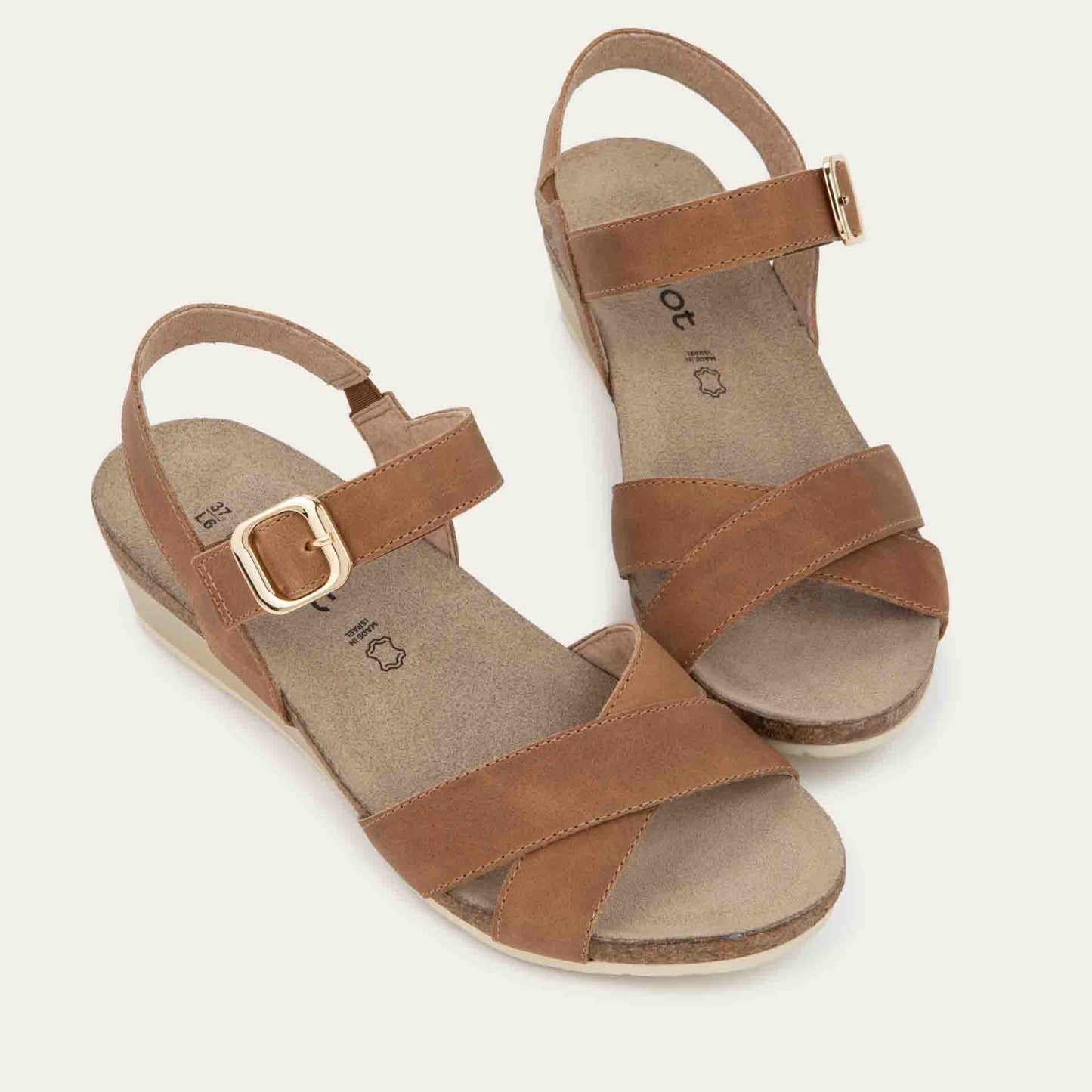 Pair of cork footbed,  brown wedge sandals with cross straps and a gold buckle on the ankle strap. 