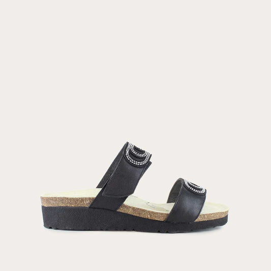 Profile view of a black leather slip on wedge sandal with two straps and reivet detailing on a cork footbed,