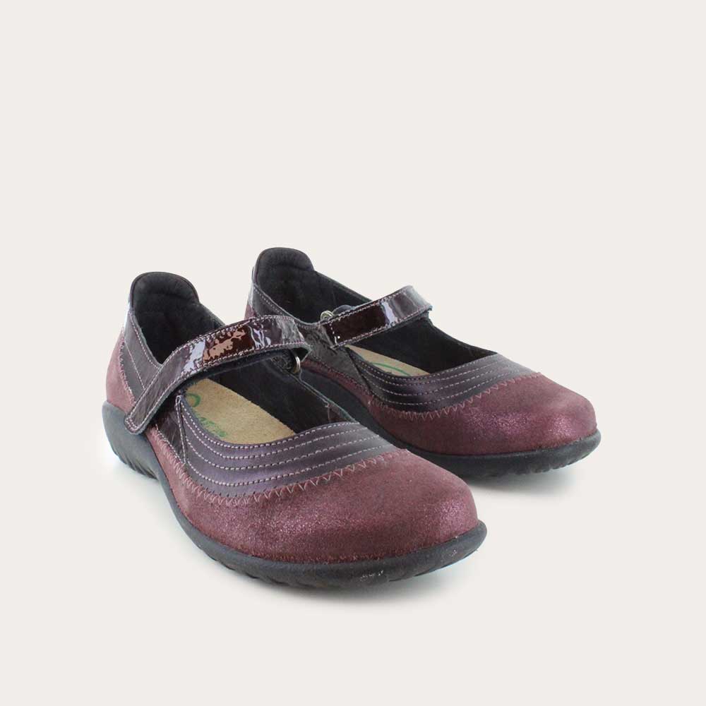Pair of  purple mary janes featuring contrasing shimmer suede and shiny leather on a black sole.