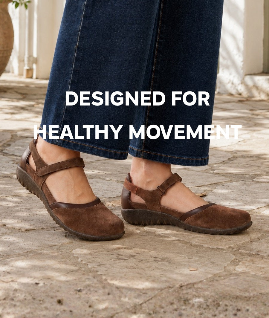 A woman in wide-leg denim walking across stone paving in brown suede Naot Mary Janes, with the words Designed For Healthy Movement set across the photo.